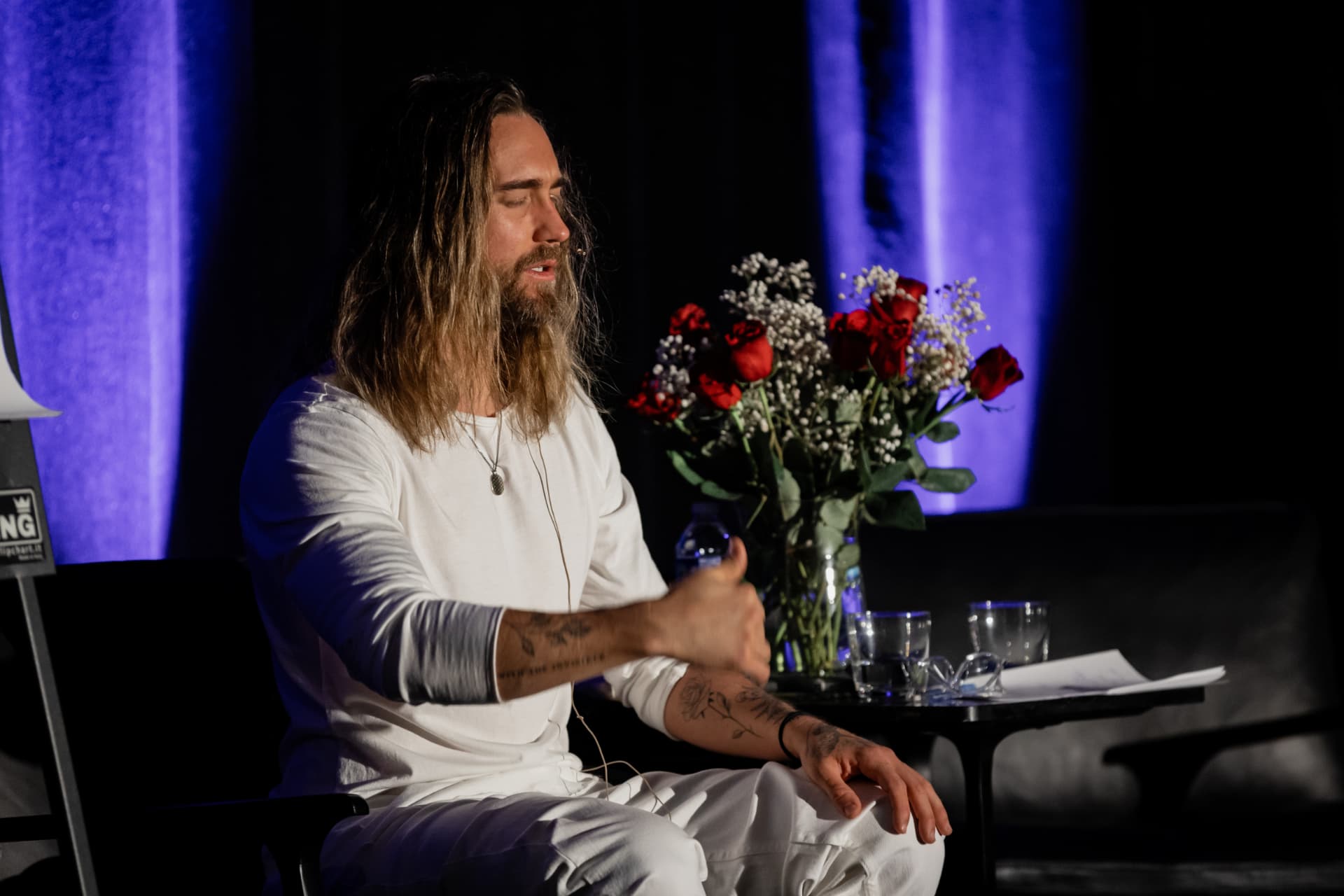 Aaron Doughty leading a guided meditation on stage at a live event