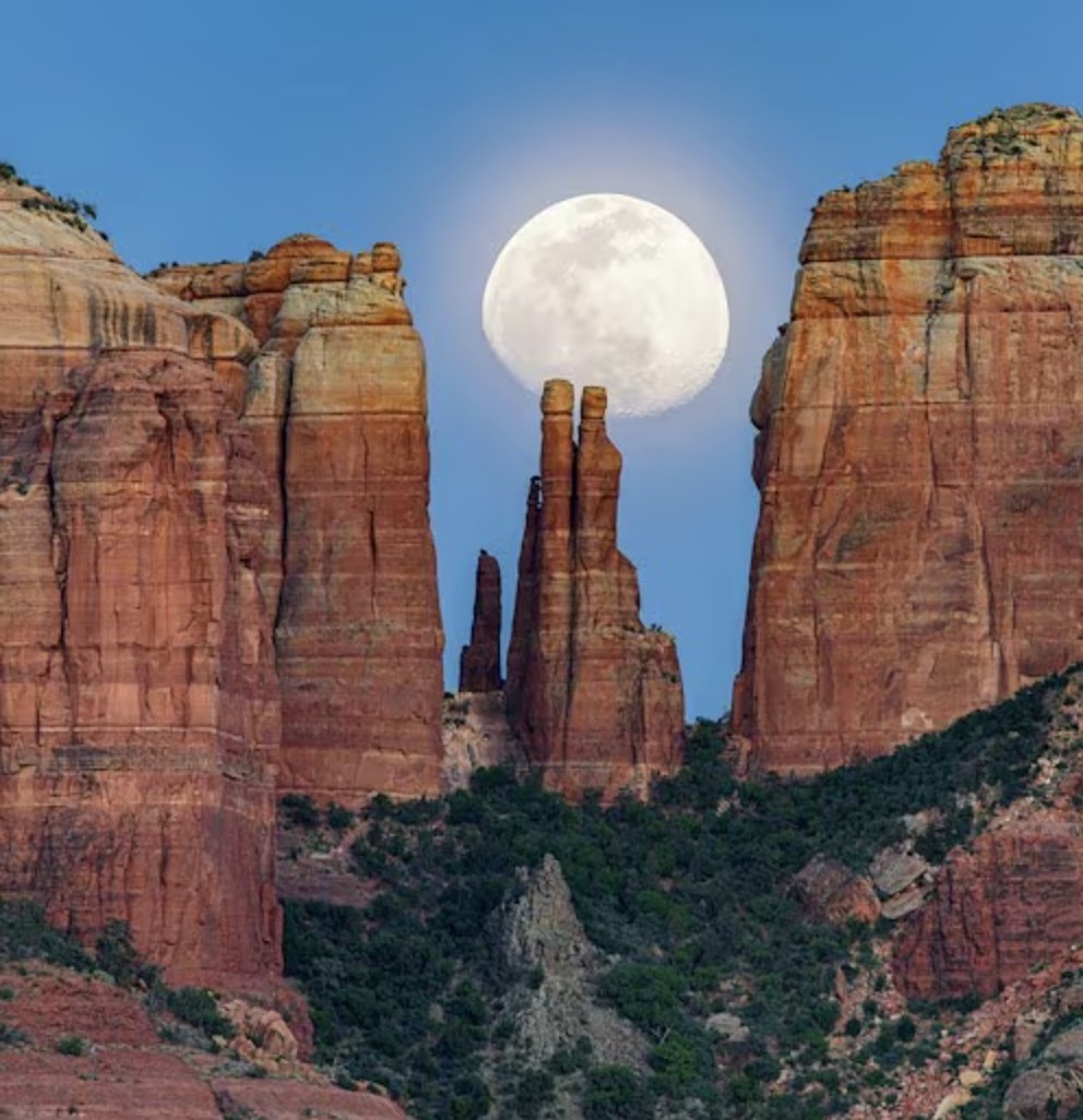 Full moon rising between the red rock spires of Cathedral Rock in Sedona